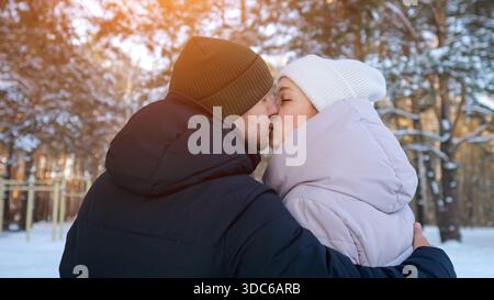 Couple fervent partage la chaleur dans un paysage froid, couple tendre baisers au milieu de la neige avec éclats de soleil lumineux, moment intime capturé comme les amoureux s'embrassent Banque D'Images