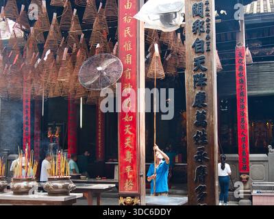 HUE-Huế-Vietnam-18 août 2019, scène à l'intérieur d'un temple chinois traditionnel montrant des dévots et des dizaines de grandes bobines d'encens suspendues en spirale brûlant, Banque D'Images
