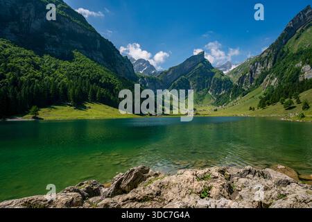 Un lac alpin tranquille reflète les sommets enneigés sous un ciel clair, évoquant la paix et l'aventure dans les Alpes suisses intactes d'Appenzell Banque D'Images