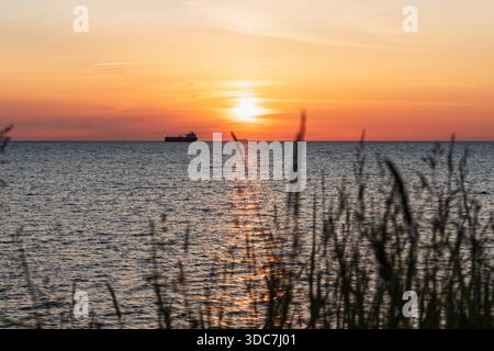Beau coucher de soleil sur la mer Baltique avec une silhouette d'un cargo à l'horizon vu de la côte estonienne. Banque D'Images