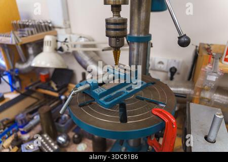 Perceuse verticale professionnelle avec foret étagé et étau bleu dans un atelier. Photo de haute qualité Banque D'Images