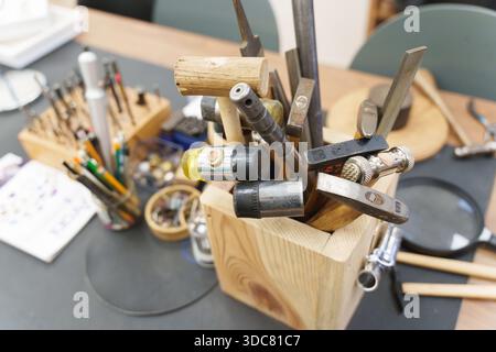 Divers marteaux et limes de bijoux professionnels stockés dans un bloc de bois sur un établi. Photo de haute qualité Banque D'Images