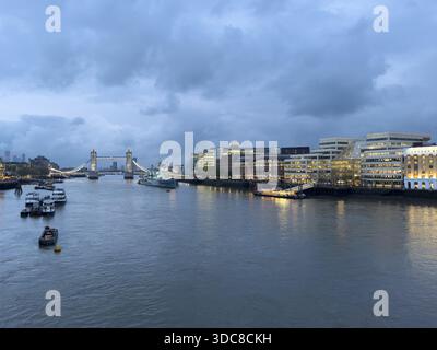 Tower Bridge brille au-dessus de la Tamise au crépuscule, avec les lumières de la ville reflétant sur l'eau. Banque D'Images