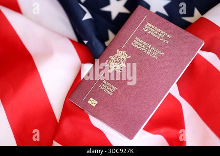 Passeport belge sur grand drapeau agitant des États-Unis d'Amérique close up. Visa AMÉRICAIN et concept d'immigration Banque D'Images