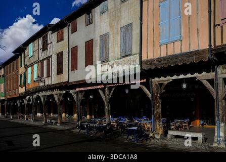 Un côté de l'une des plus belles places de marché à arcades de France : la place du Maréchal-Leclerc, la place des couverts ou les couverts à Mirepoix, une bastide fortifiée entre Carcassonne et Foix en Ariège, Occitanie. Les étages supérieurs des maisons médiévales à volets en bois reposent sur des piliers en chêne, avec des galeries couvertes au rez-de-chaussée abritant des cafés, des boutiques et des restaurants en trottoir. Banque D'Images