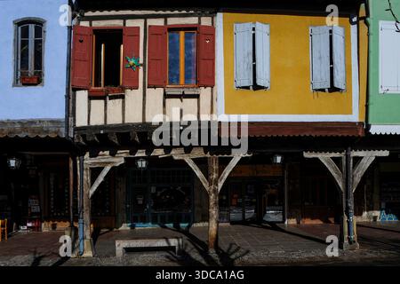 Les galeries couvertes du rez-de-chaussée abritent des cafés, des restaurants et des boutiques sur l'une des plus belles places de marché à arcades de France, la place du Maréchal-Leclerc, la place des couverts ou les couverts à Mirepoix, une bastide fortifiée entre Carcassonne et Foix en Ariège, Occitanie. Au-dessus, reposant sur des piliers de chêne, se trouvent les étages supérieurs à volets en bois des maisons médiévales. Banque D'Images