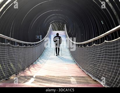 Oberhausen, Allemagne. 21 décembre 2025. Un jogger traverse le pont « Slinky Springs to Fame » sur le canal Rhin-Herne dans le Kaisergarten par des températures agréables qui sont trop élevées pour la période de l'année. Les météorologues prédisent des températures plus basses pour la semaine de Noël, mais avec beaucoup de soleil. Crédit : Roberto Pfeil/dpa/Alamy Live News Banque D'Images