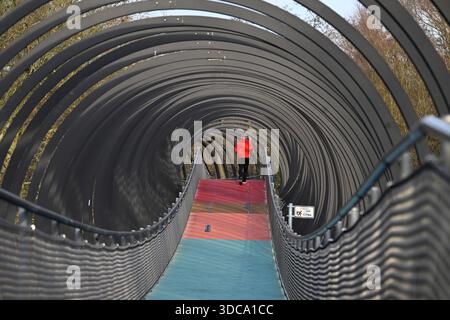 Oberhausen, Allemagne. 21 décembre 2025. Un jogger traverse le pont « Slinky Springs to Fame » sur le canal Rhin-Herne dans le Kaisergarten par des températures agréables qui sont trop élevées pour la période de l'année. Les météorologues prédisent des températures plus basses pour la semaine de Noël, mais avec beaucoup de soleil. Crédit : Roberto Pfeil/dpa/Alamy Live News Banque D'Images