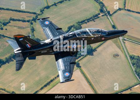 Un entraîneur avancé BAE Systems Hawk T.2 de la Royal Air Force, immatriculé ZK021, photographié lors d'une séquence air-air au Royal International Air Tattoo, RAF Fairford, Angleterre. La vue rapprochée met en évidence la zone du poste de pilotage avec le pilote assis sous la verrière. Le Hawk T.2 constitue un élément clé de la formation à jet rapide de la RAF, offrant une manipulation réaliste et une préparation des systèmes pour le service de première ligne. Banque D'Images