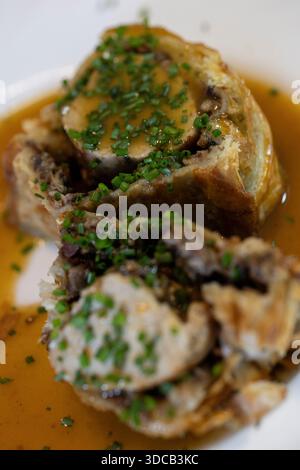 wellington de bœuf en tranches servi avec sauce riche et ciboulette fraîche Banque D'Images