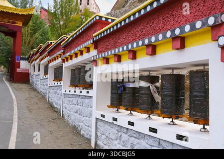 Mouvement rituel et répétition, roues de prière bordant le chemin d'entrée d'un monastère bouddhiste tibétain au Ladakh, Himalaya, Inde. Banque D'Images