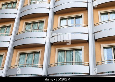 Façade d'immeuble résidentiel contemporain dotée de balcons incurvés, de murs beiges et de grandes fenêtres en verre. Cette image capture la vie urbaine Architec Banque D'Images
