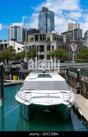 Des yachts et des bateaux à moteur de luxe accostent dans le vibrant Viaduct Harbour avec l'horizon d'Auckland et l'architecture moderne du quartier des affaires en arrière-plan. Banque D'Images
