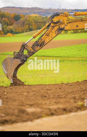 Gros plan d'un godet d'excavatrice déplaçant la terre entourée de champs verts, transition énergétique, construction d'un espace ouvert PV, Bade-Wuerttemberg, Allemagne Banque D'Images