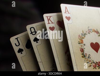 Gros plan de quatre cartes à jouer vintage avec jack, reine, roi et as sur un fond sombre. Idéal pour les thèmes de casino, le contenu de poker, le luxe Banque D'Images