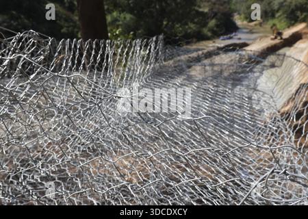 Filet métallique solide en maille de gabion posé sur le sol pour le contrôle de l'érosion près du site de construction de la rive illustrant la résistance protectrice et le poignet Banque D'Images