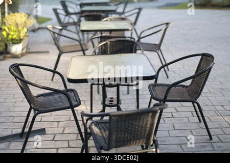 Terrasse de café extérieur vide avec chaises en métal noir et tables carrées disposées sur un trottoir en pierre grise attendant les clients pour profiter de relaxin Banque D'Images