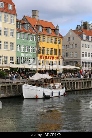 Copenhague, Danemark-septembre 19,2025:personnes non identifiées mangeant, buvant, assis et parlant par bateau blanc et bâtiments historiques à Nyhavn Banque D'Images