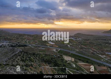 Vue aérienne des rayons du soleil traversant les nuages au-dessus de la mer Méditerranée et des champs cultivés, Mellieha, Malte. Banque D'Images