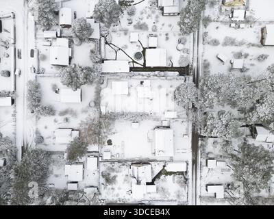 Vue aérienne de maisons et d'arbres recouverts de neige, transformant le paysage en un pays des merveilles hivernales sereines, Bestensee, Brandebourg, Allemagne. Banque D'Images
