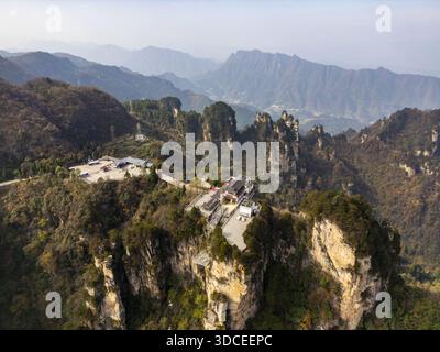 Vue aérienne de majestueux piliers de grès percer la chaîne de montagnes Tianzi voilée de brume, projetant de longues ombres à travers le paysage accidenté, Zhangjiajie, Banque D'Images