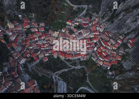 Vue aérienne de l'ancien village niché parmi les sommets déchiquetés, toits en terre cuite brillants dans la lumière de décoloration, contrastant avec la pierre grise rugueuse, C Banque D'Images