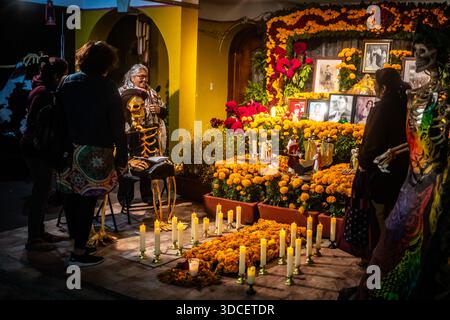 Oaxaca, Mexique - 03 novembre 2023 : vue d'une journée vibrante de l'autel mort échoue à la lumière des chandelles, encadrée par des soucis et des photographies, comme People gath Banque D'Images