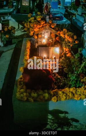 Oaxaca, Mexique - 03 novembre 2023 : vue de souliers vibrants ornant les tombes dans un cimetière pendant Dia de los Muertos, baigné dans la douce lueur de cand Banque D'Images