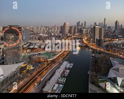 Vue aérienne d'une rivière reflétant les lumières de la ville, avec des ponts illuminés et des gratte-ciel perçant la ligne d'horizon, Tianjin, Tianjin, Chine. Banque D'Images