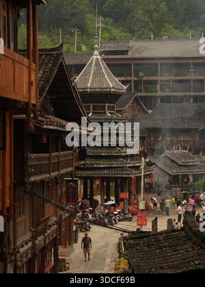 Qiandongnan, Chine - 30 septembre 2025 : vue sur un bâtiment traditionnel de style pagode au milieu d'une place de ville animée, ses toits à plusieurs étages contrastent avec le Banque D'Images