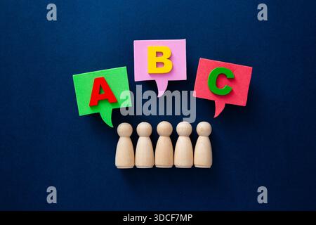 Figurines de personnes en bois apprenant des lettres abc à partir de bulles de discours colorées Banque D'Images