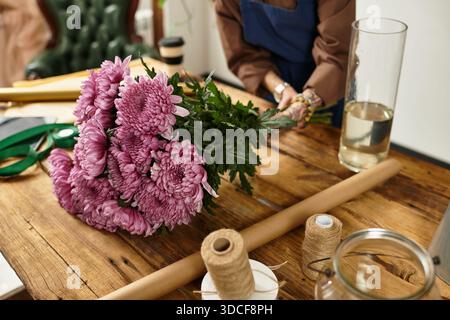 Jeune fleuriste prépare de belles fleurs roses pour les clients dans sa boutique. Banque D'Images