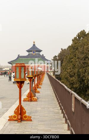 Vue de la salle de prière du Temple du ciel pour de bonnes récoltes encadrée par des lanternes oranges traditionnelles et de la pierre altérée, Pékin, Pékin, Chine. Banque D'Images