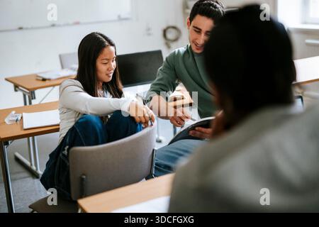Vue en angle élevé d'une jeune étudiante étudiante avec un ami masculin assis sur une chaise dans la salle de classe Banque D'Images