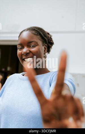 Portrait d'une jeune femme souriante montrant un signe de paix Banque D'Images