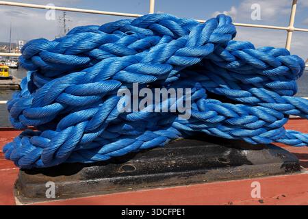 Corde d'amarrage bleue robuste enroulée sur le pont du navire. Banque D'Images