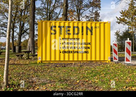 Conteneur d'expédition jaune de Stedin avec texte d'avertissement de sécurité, entouré de feuilles d'automne et d'arbres dans une zone de parc public. Utrecht, pays-Bas, 2 N Banque D'Images