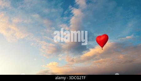 Fond romantique avec ballon en forme de coeur rouge vif volant dans le ciel du coucher du soleil, espace libre pour le texte, adapté à la Saint-Valentin Banque D'Images