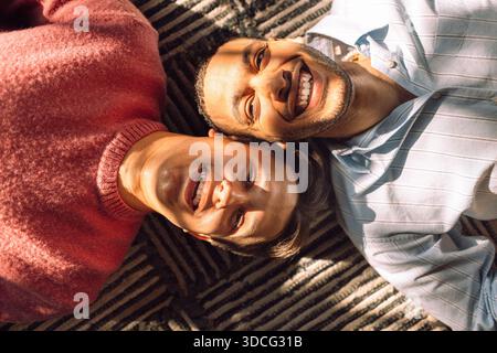 Portrait en angle élevé d'un jeune homme souriant couché à côté d'un ami masculin Banque D'Images