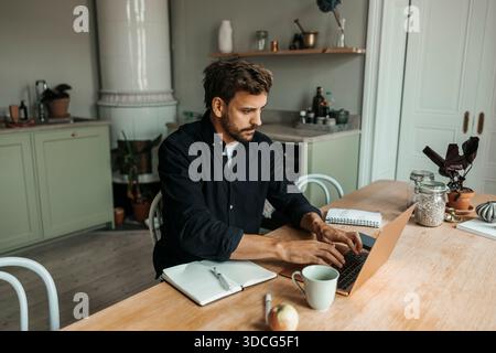 Vue en angle élevé d'un indépendant masculin focalisé travaillant sur un ordinateur portable à la maison Banque D'Images