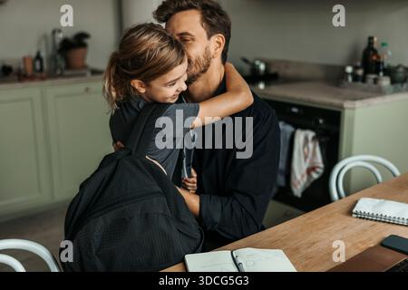 Père embrassant sa fille revenant de l'école à la maison Banque D'Images