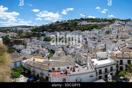 Setenil de las Bodegas, Espagne - 7 mai 23 : une vue panoramique d'un village blanchi à la chaux niché dans un paysage vallonné sous un ciel bleu vif avec c moelleux Banque D'Images