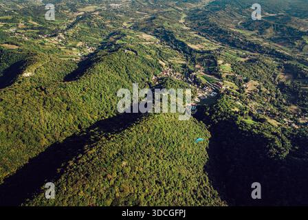 Vue aérienne de la vibrante, luxuriante, forêt verte contrastant avec le petit village niché au milieu des collines, Prodin Dol, Zagrebacka zupanija, C. Banque D'Images
