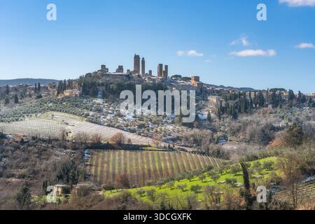 Vue hivernale de la ville médiévale de San Gimignano couverte de neige légère. Vignes enneigées et oliviers dans la campagne toscane, province de Sienne, il Banque D'Images