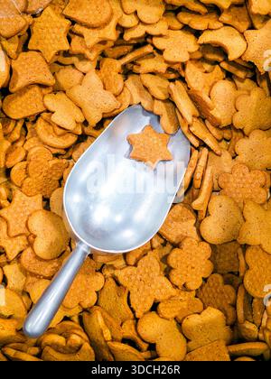 Vue de dessus de biscuits assortis en pain d'épices dans des formes festives avec une pelle en métal tenant un biscuit étoilé, symbolisant la cuisson, les fêtes et les friandises saisonnières Banque D'Images