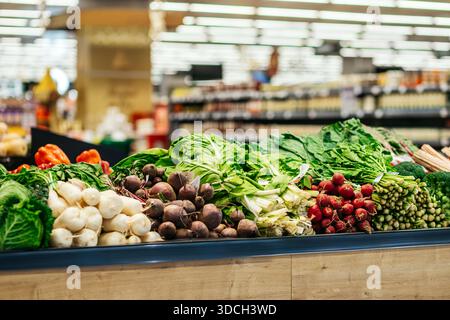 Légumes colorés disposés sur l'affichage en bois dans l'épicerie, mettant en évidence les options de produits frais et favorisant des choix alimentaires sains pour les clients Banque D'Images