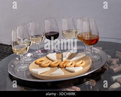 Verres de dégustation DE VINS ESPAGNOLS situation en plein air sélection de vins rouges et blancs, fromage et biscuits secs sur le bout du tonneau avec bouchons de bouteilles Îles Canaries Espagne.les îles Canaries se vantent de cépages indigènes uniques prospérant dans le sol volcanique, y compris les blancs comme Listán Blanco (Palomino), Malvasía Volcánica aromatique et Marmajuelo, aux côtés de rouges tels que Negramoll, un raisin léger et à base de plantes semblable au Pinot Noir, plus d'autres comme Gual, Verdello, Albillo Criollo et Moscatel. Banque D'Images