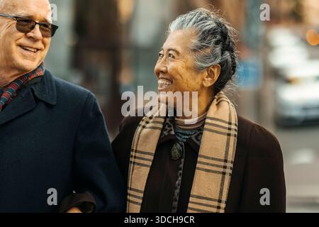 Femme âgée souriante appréciant le temps de loisirs avec l'homme dans la rue Banque D'Images
