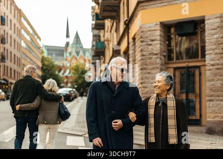 Heureux couple senior traversant la route avec bras dans bras à la rue Banque D'Images