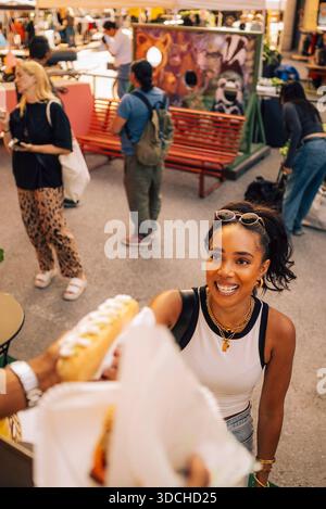 Vue en angle élevé de la femme souriante achetant le hot-dog au camion de nourriture Banque D'Images